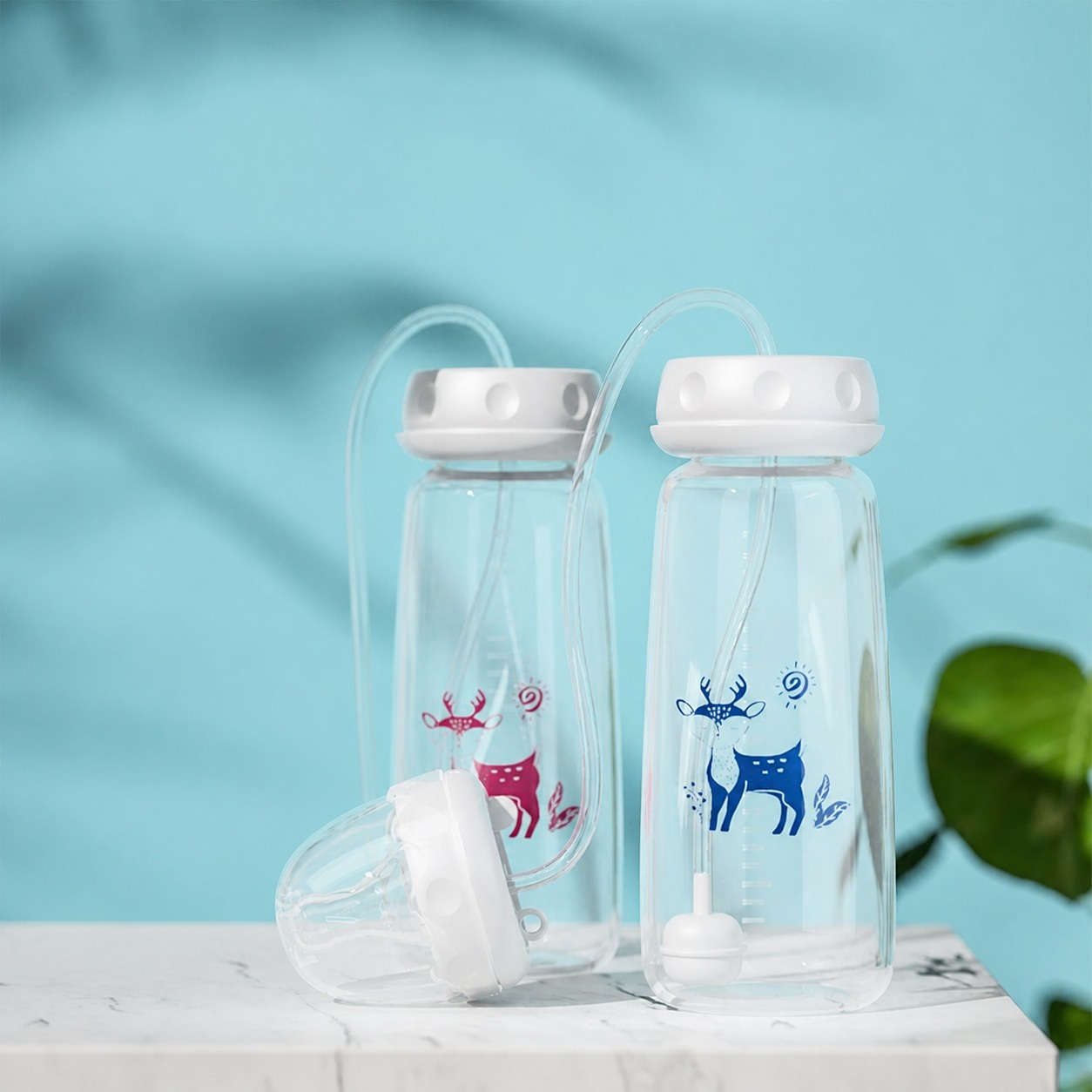 Pink and blue hands-free baby feeding bottles with tube and nipple assembly