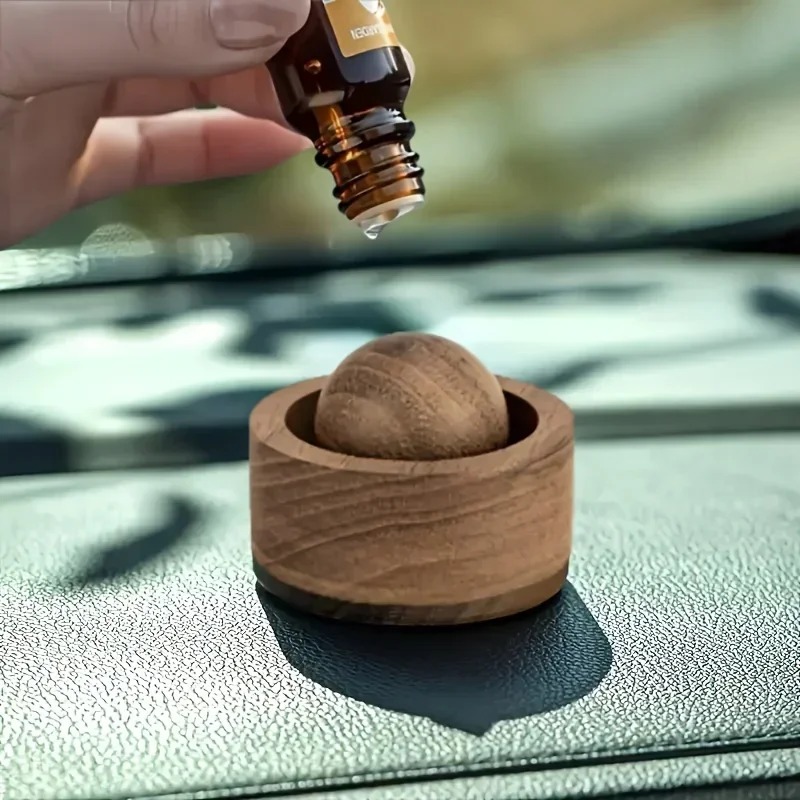 Essential oil being applied to a wooden aroma diffuser on a car dashboard